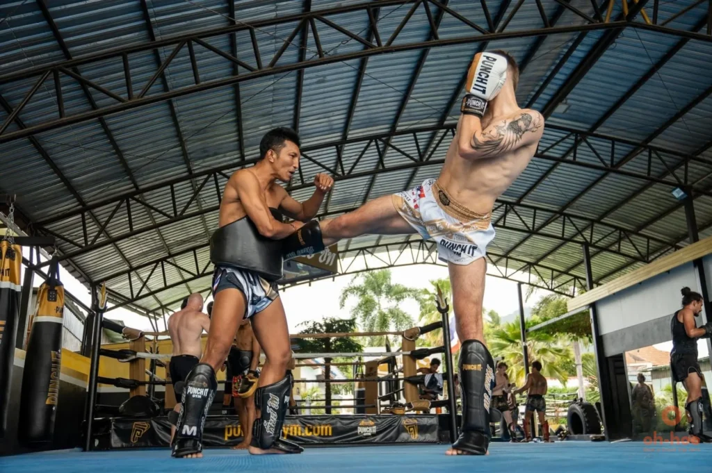 Tourist practicing Muay Thai pad work with a professional Thai trainer during a beginner class in Koh Samui