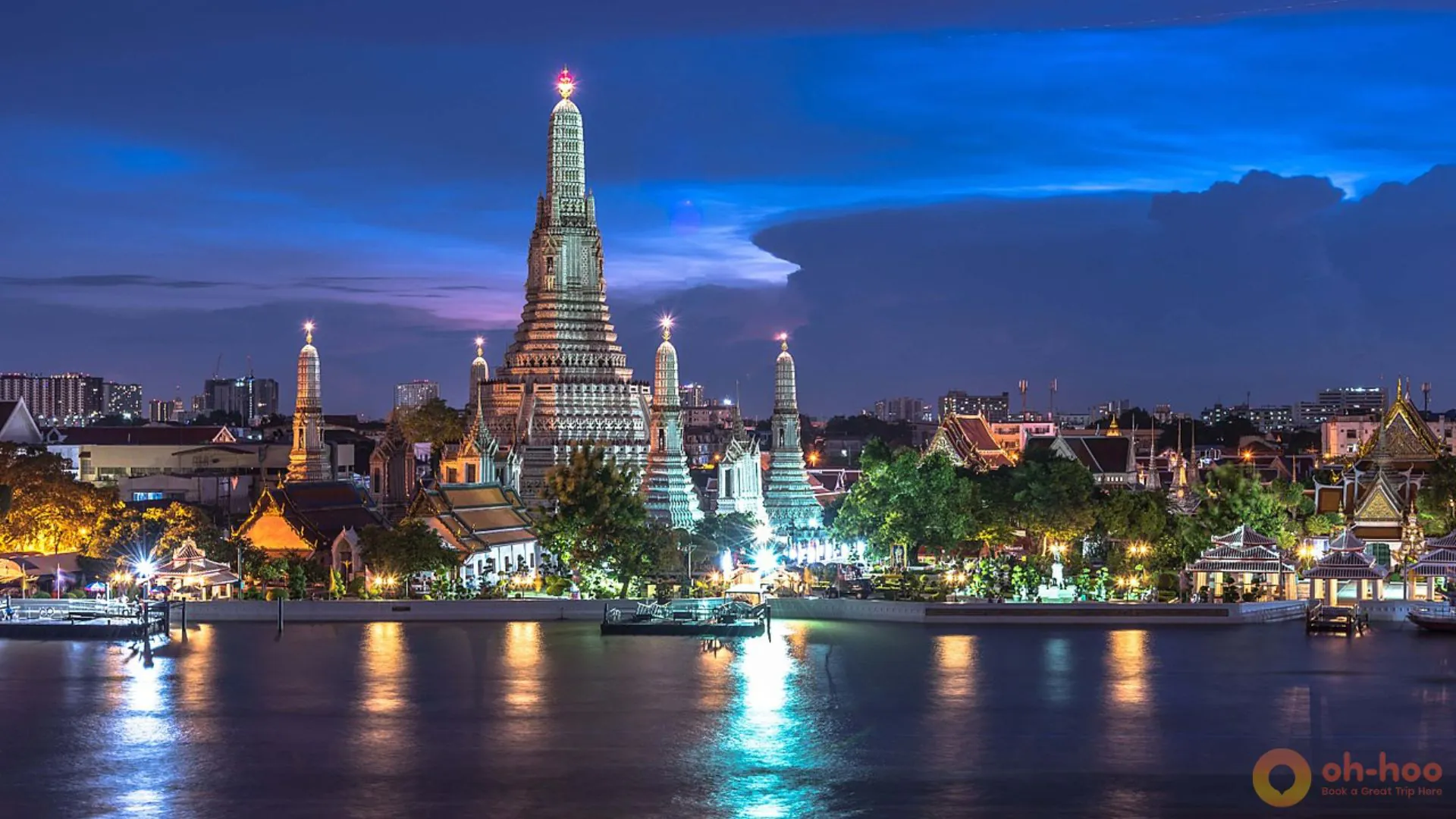 Wat Arun temple illuminated at night beside the Chao Phraya River in Bangkok, Thailand