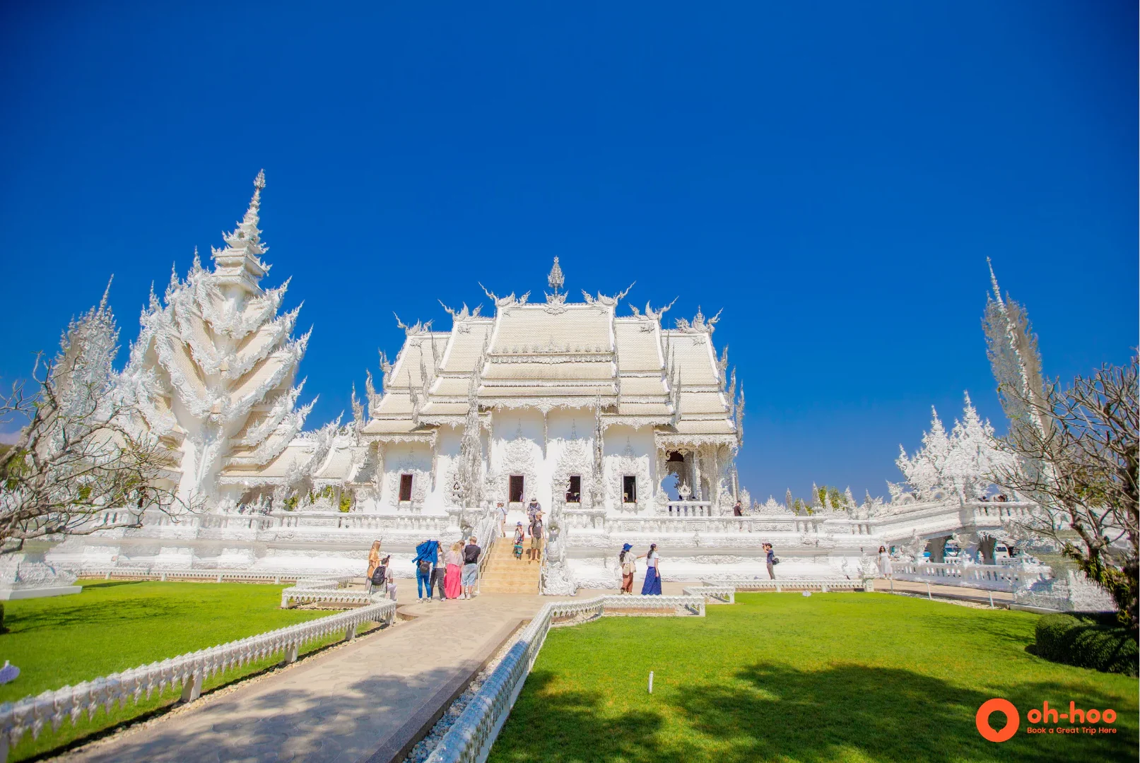 The ornate white exterior of Wat Rong Khun, the White Temple Chiang Rai, under a blue sky