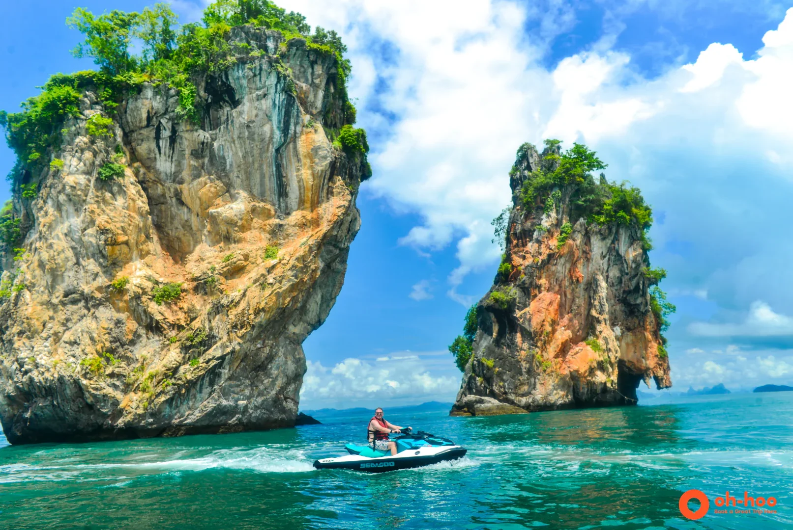 Jet skier speeding past towering limestone rocks in the turquoise waters of Phuket