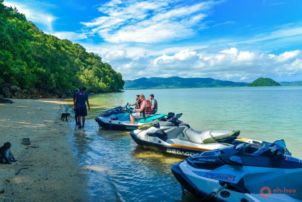 Guided jet ski group stopping at an island beach with monkeys during a jet ski tour in Phuket