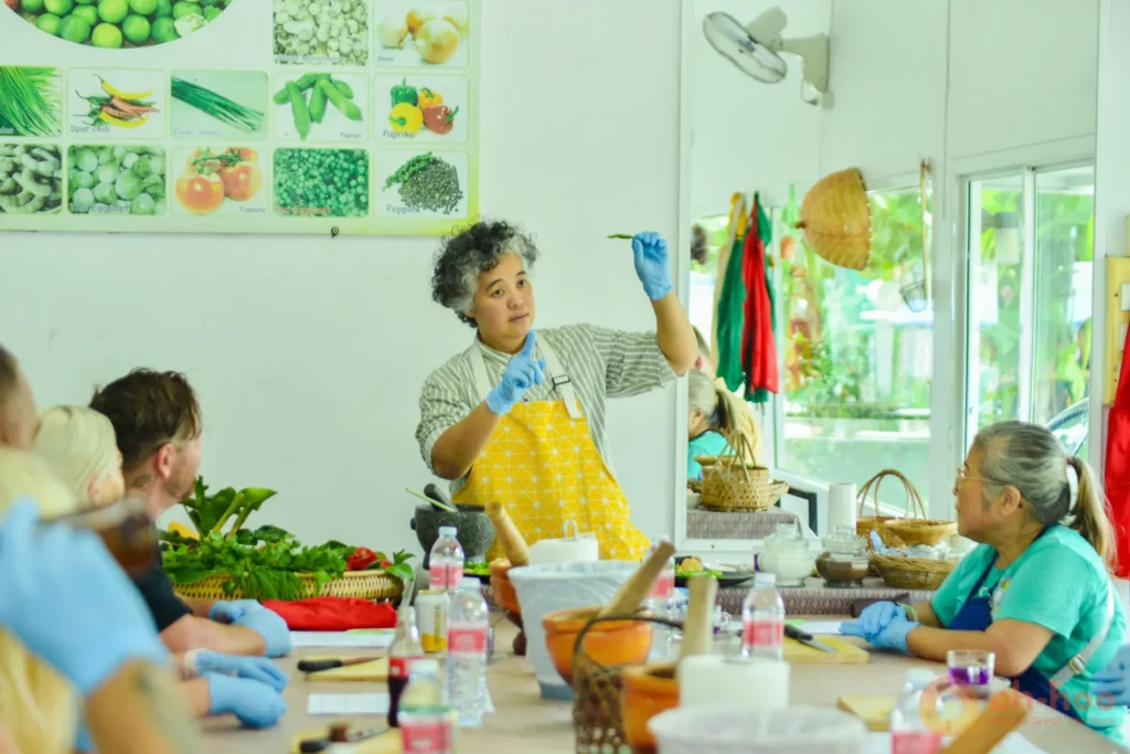 Small group Thai cooking class in Phuket with a chef teaching curry ingredients around the prep table