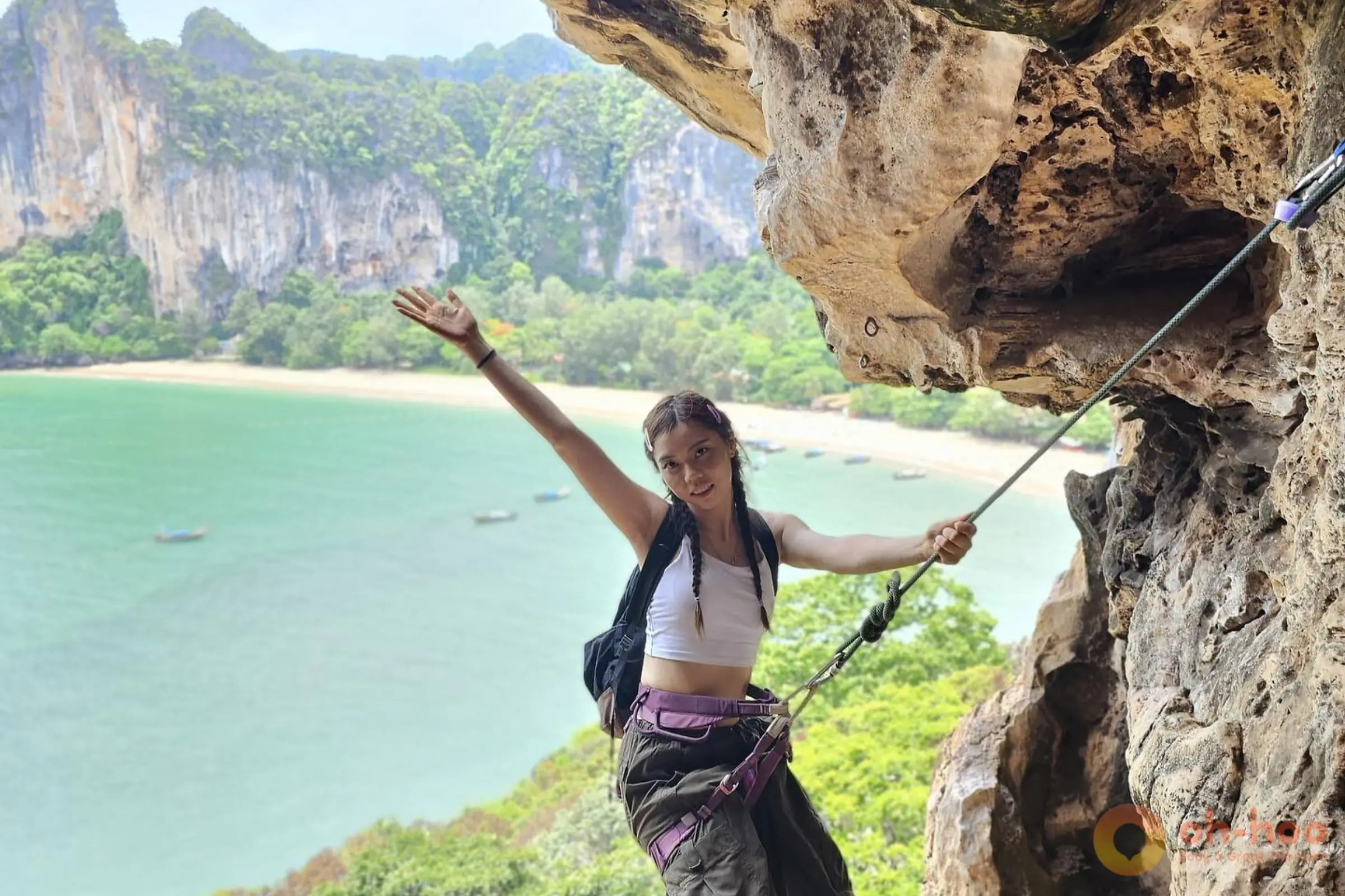 Climber standing on limestone cliff with beach view during a Railay rock climbing tour