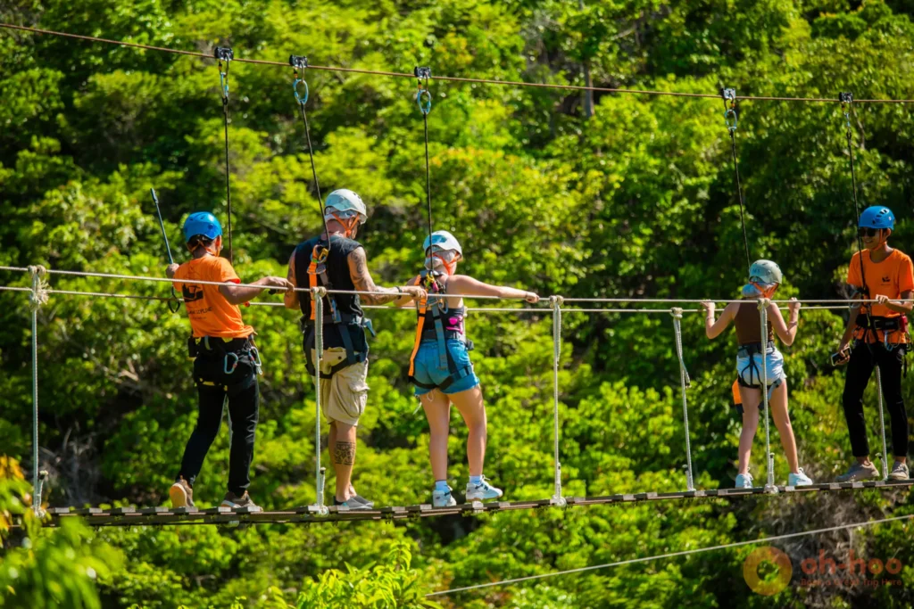 A group crossing the suspended Sky Bridge walkway through the treetops at the Koh Phangan zipline sky adventure park