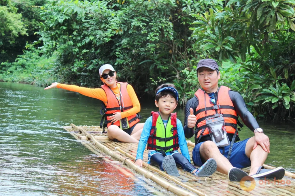 Tourists on bamboo raft in Khao Lak with dry bags for splash protection