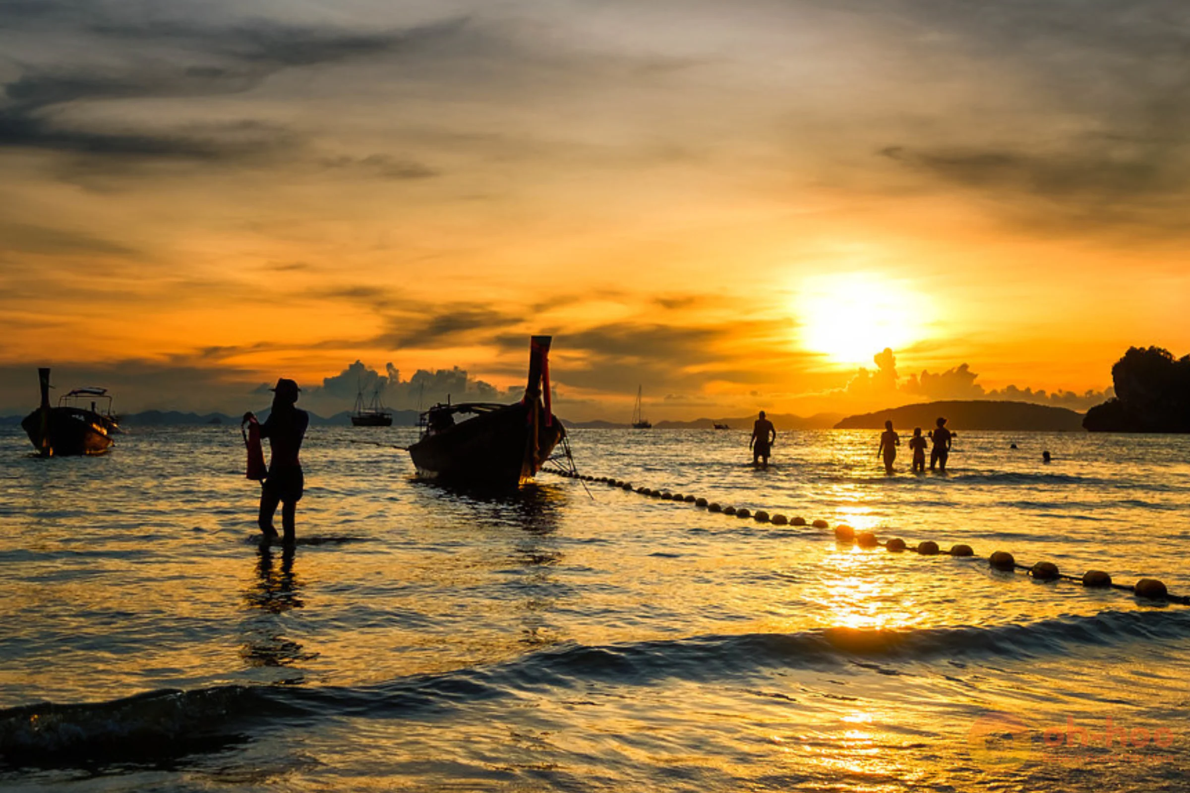 Golden-hour sun setting over the Andaman Sea with longtail boats silhouetted on a Krabi 7 Islands sunset tour
