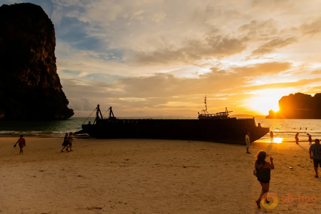 Golden sunset over the sea with longtail boats silhouetted and people on the beach on a Krabi 7 Islands sunset tour