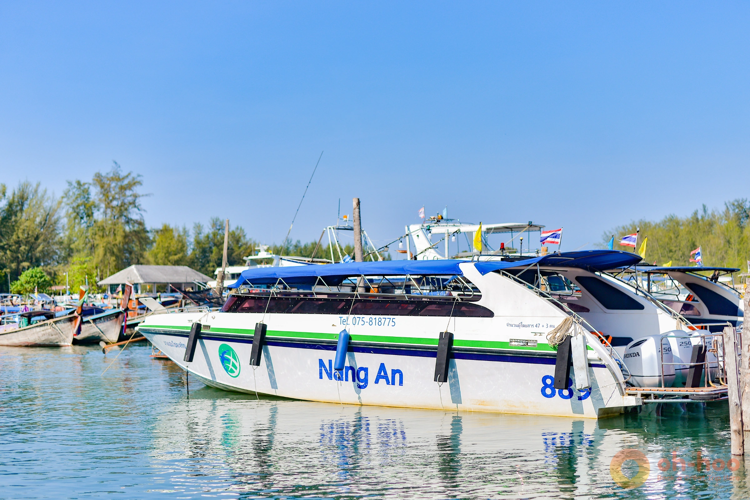 Longtail and speedboats at a white-sand beach with a limestone island behind on the Krabi 4 Islands hopping tour