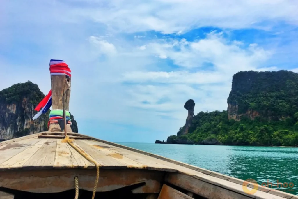 The iconic chicken-head shaped limestone rock formation at Chicken Island (Koh Kai) in Krabi with longtail boats on turquoise water.