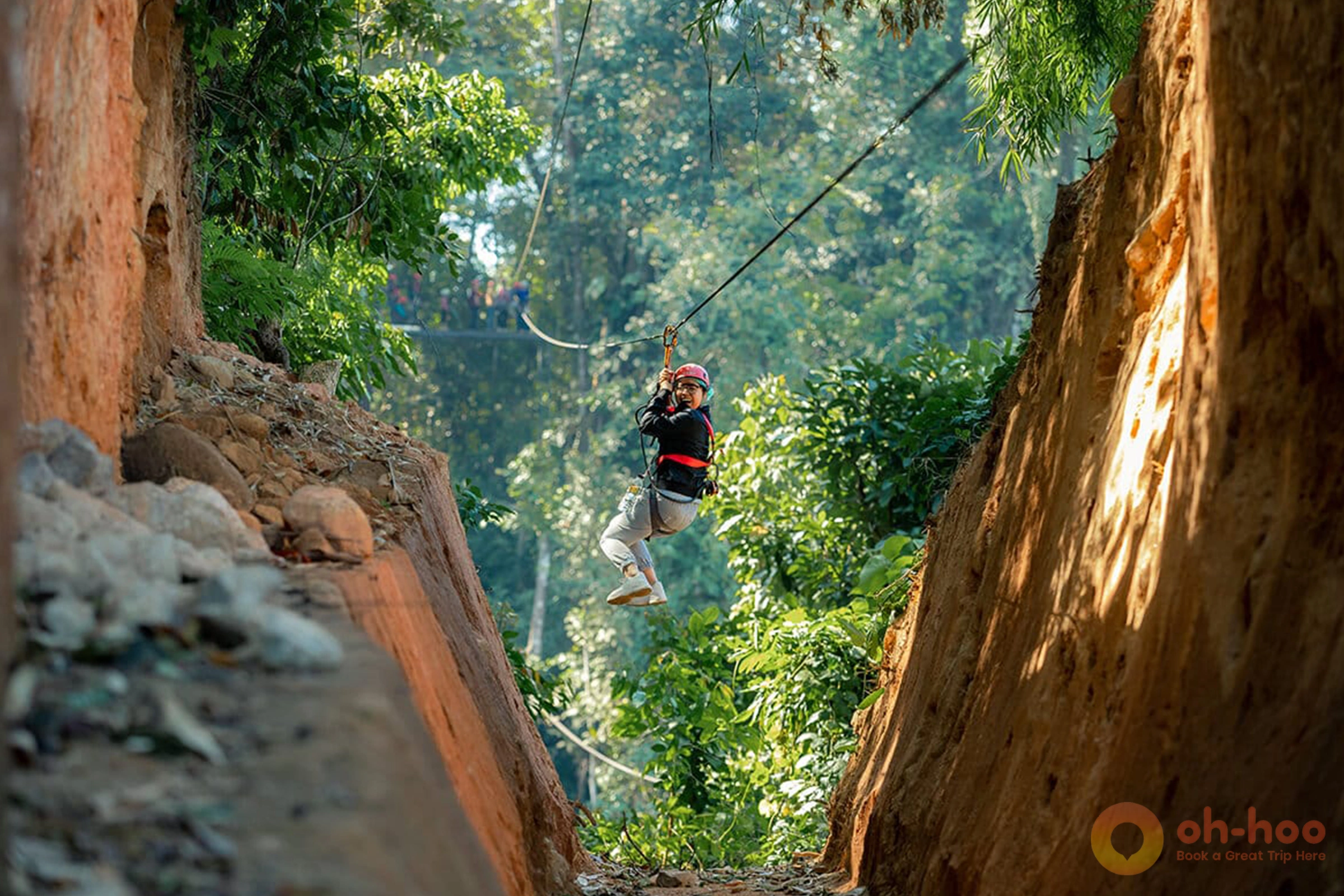 Young woman gliding on a zipline cable through lush rainforest canopy in Chiang Mai
