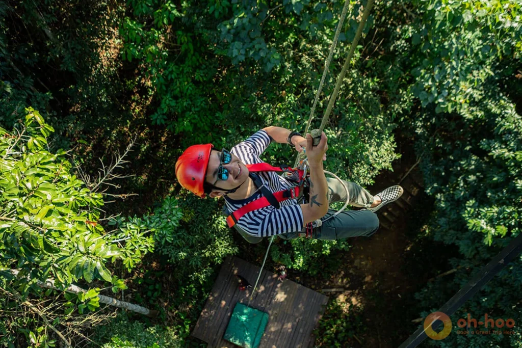 Adventurer abseiling down from a high tree platform during a Chiang Mai zipline tour
