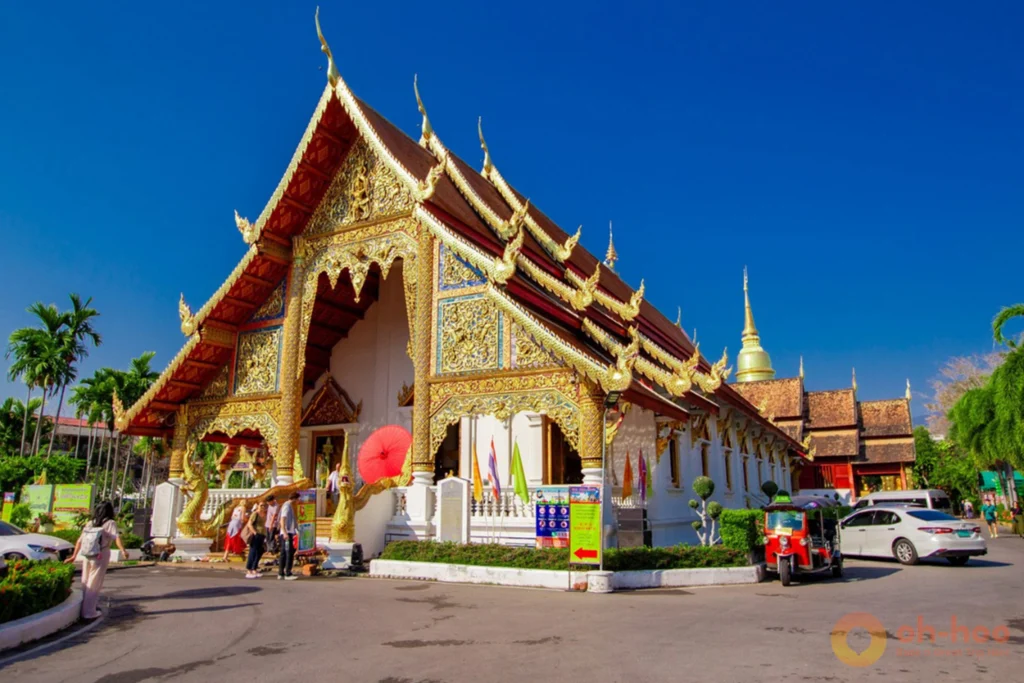 Red tuk-tuk parked in front of traditional Lanna temple architecture at Wat Phra Singh Chiang Mai