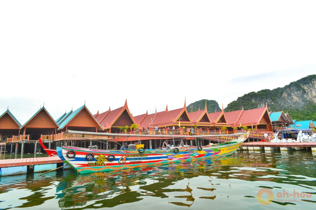 Traditional wooden stilt houses and colorful local longtail boats along the water edge in Koh Panyee floating village