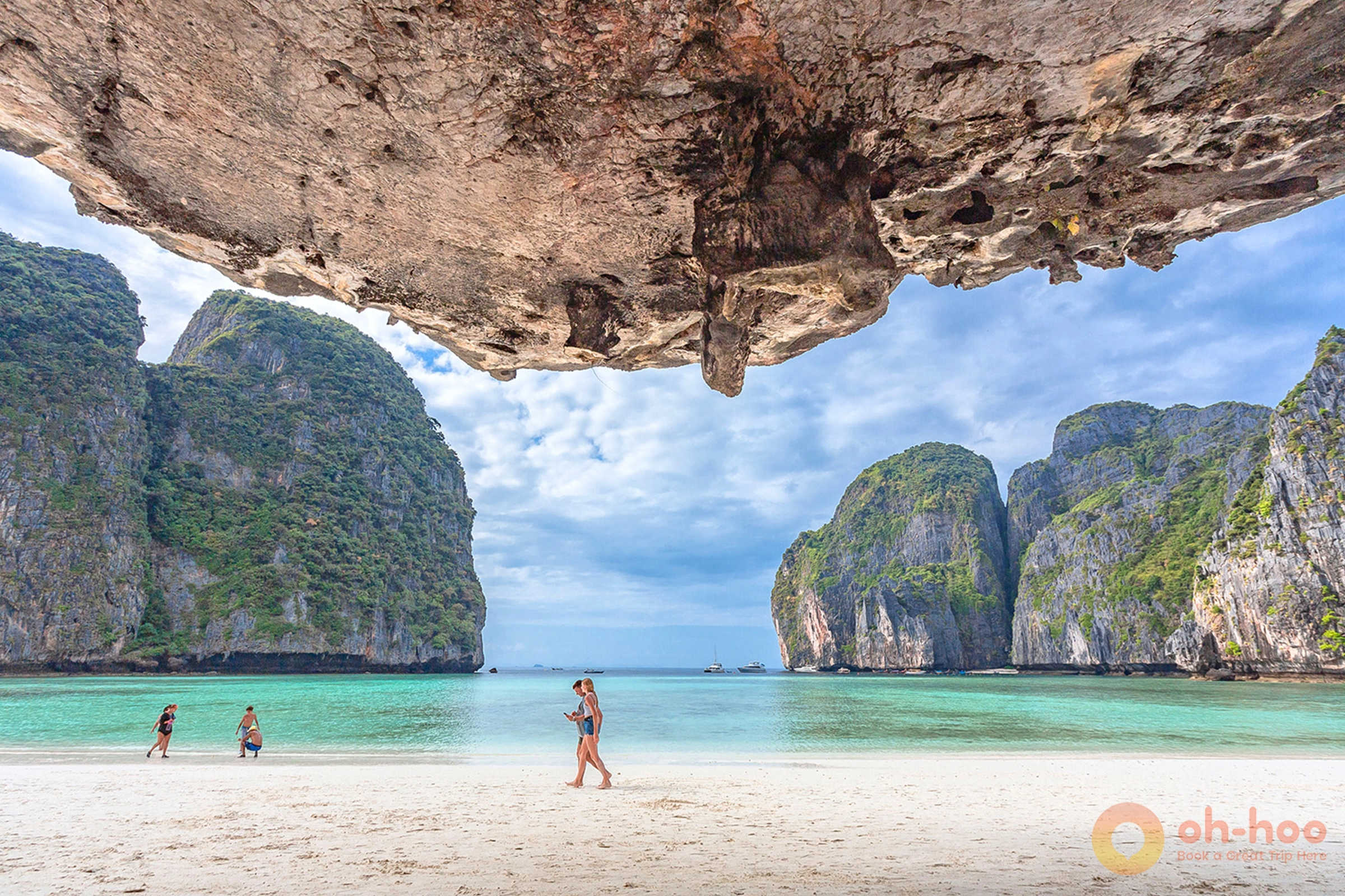 Traveler standing on the pristine white sand beach of Maya Bay surrounded by limestone cliffs