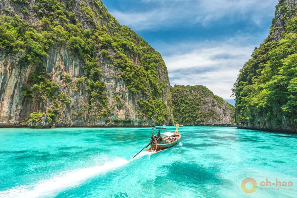 Traditional longtail boat anchored in the crystal-clear turquoise emerald waters of Pileh Lagoon near Maya Bay