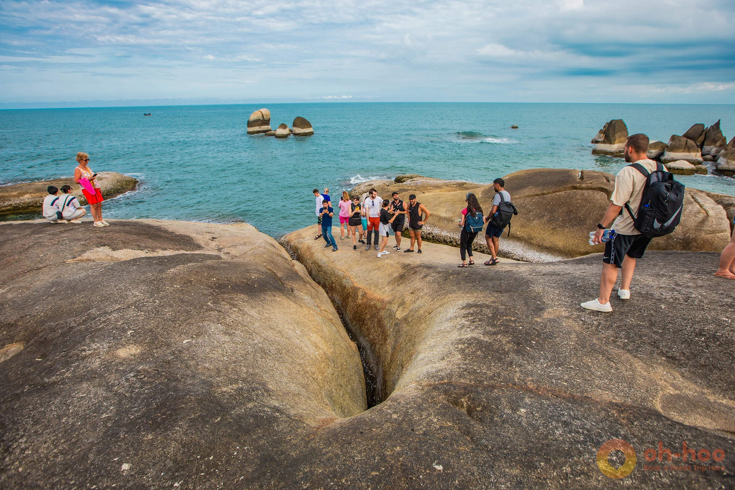 A tourist stands smiling on the large Hin Ta and Hin Yai rocks in Koh Samui.