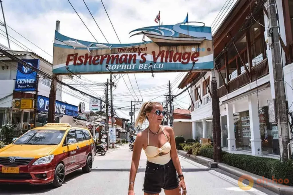 Tourist standing near the iconic Fisherman's Village Bophut Beach sign in Koh Samui.