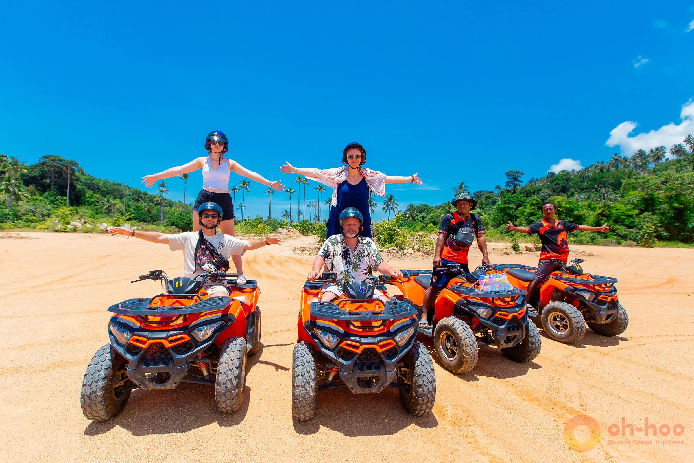 Group of tourists posing happily on orange quad bikes in Koh Phangan.