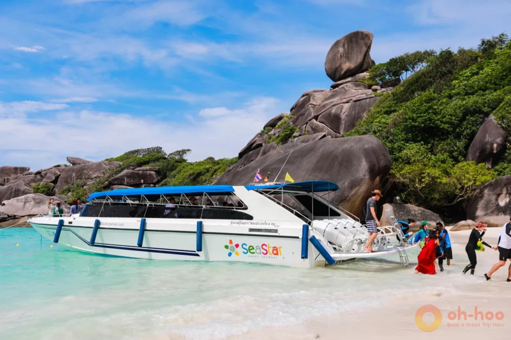 Speedboat anchored near a powdery white sand beach with clear blue waters and granite rock formations at the Similan Islands.