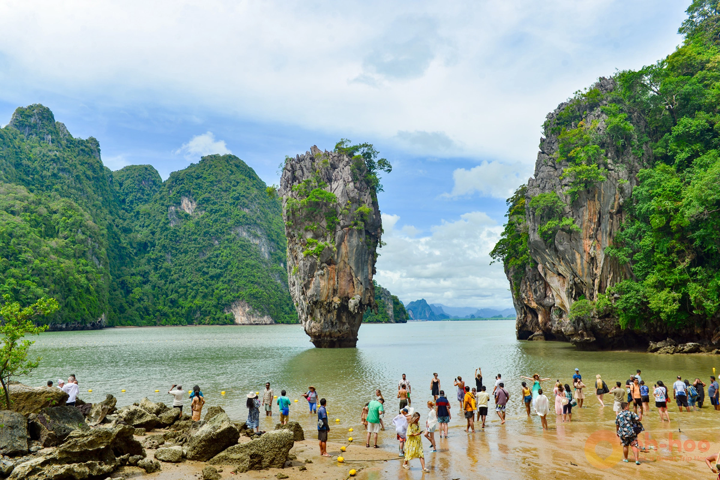 Tourists gathered on the beach at Khao Phing Kan, taking photos of the iconic limestone karst spire of Koh Tapu in Phang Nga Bay.