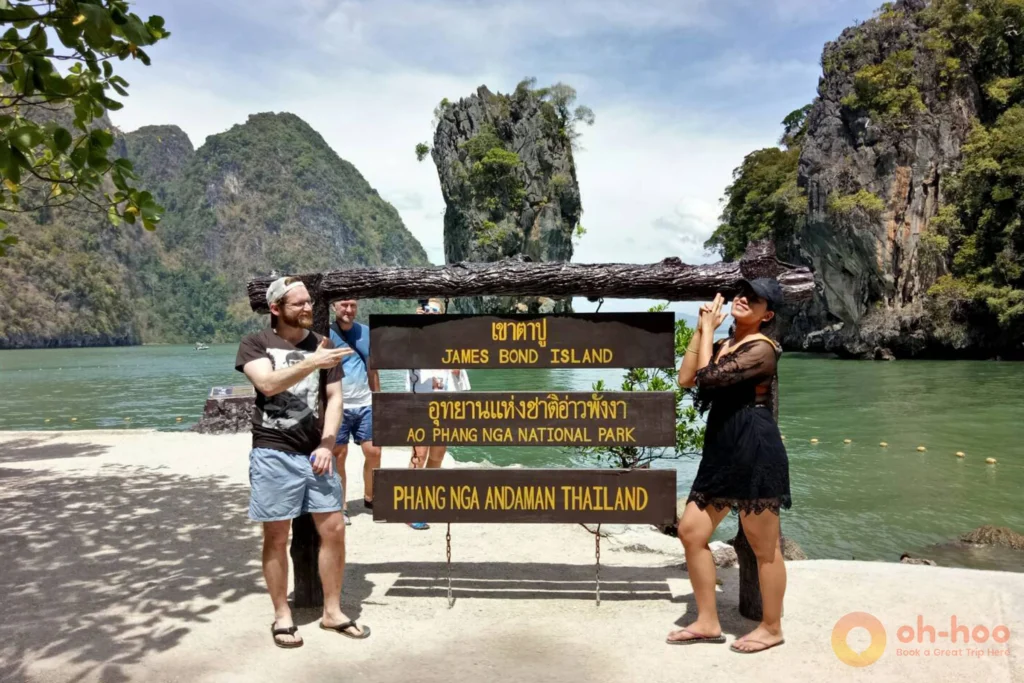 A happy couple posing cheerfully behind the engraved Ao Phang Nga National Park sign at James Bond Island.