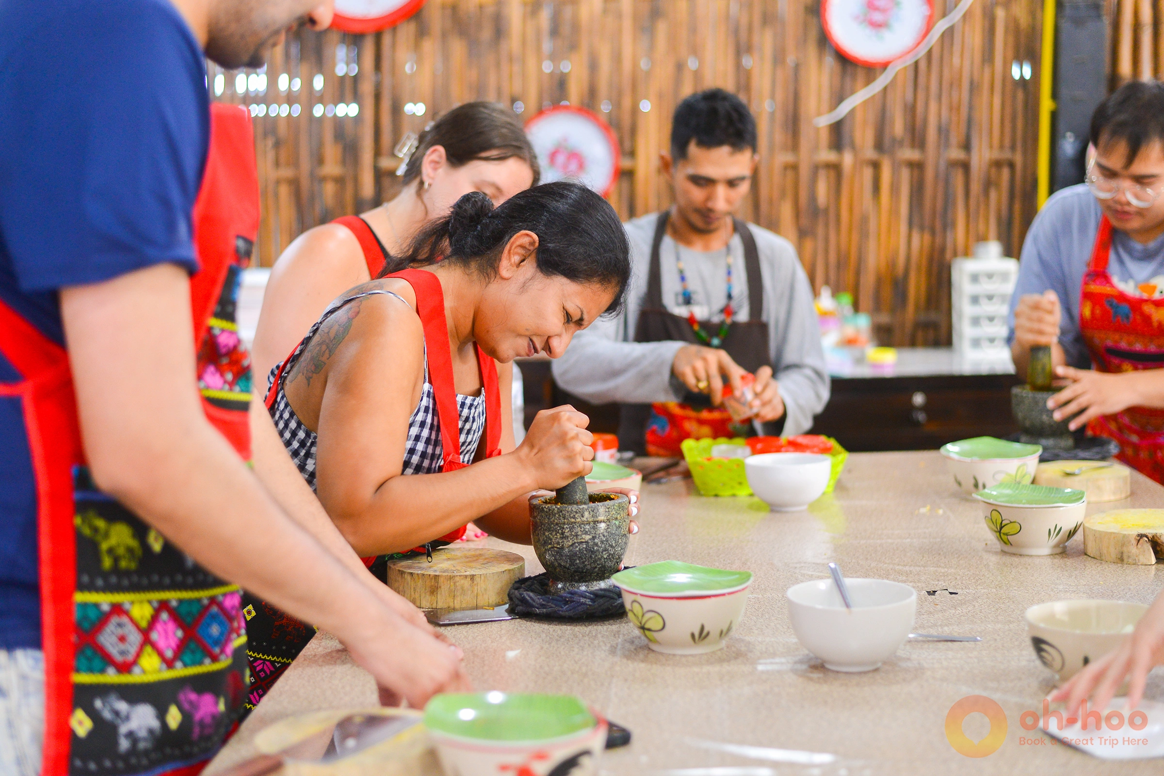 Hands pounding fresh Thai curry paste in a stone mortar at an Ao Nang cooking class
