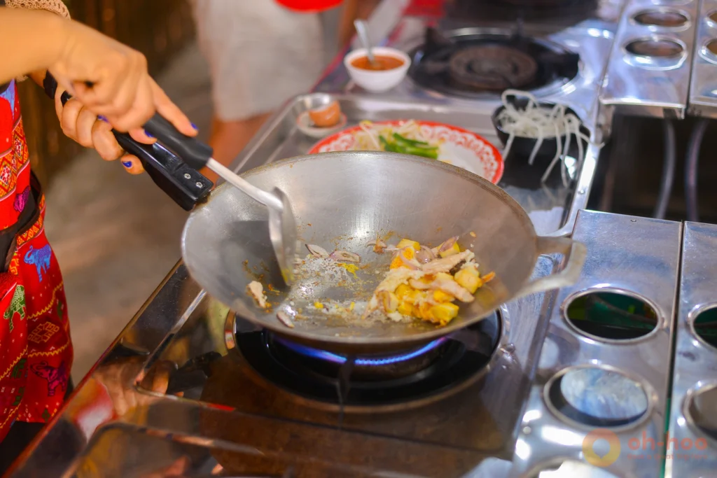 Flames leaping from a wok as a student stir-fries at an Ao Nang cooking class