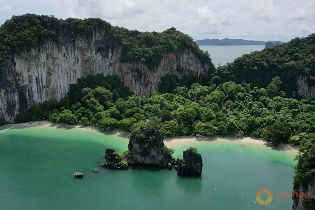 Lush green Krabi cliffs under dramatic monsoon clouds with a full waterfall