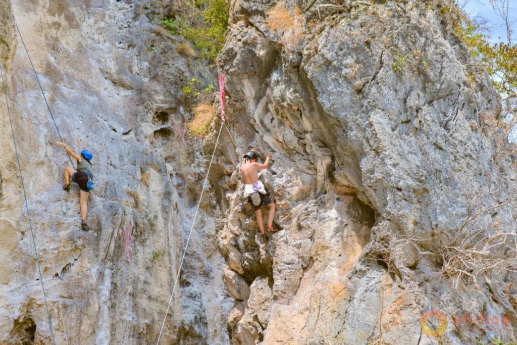Rock climber scaling a limestone cliff above the sea at Railay Beach