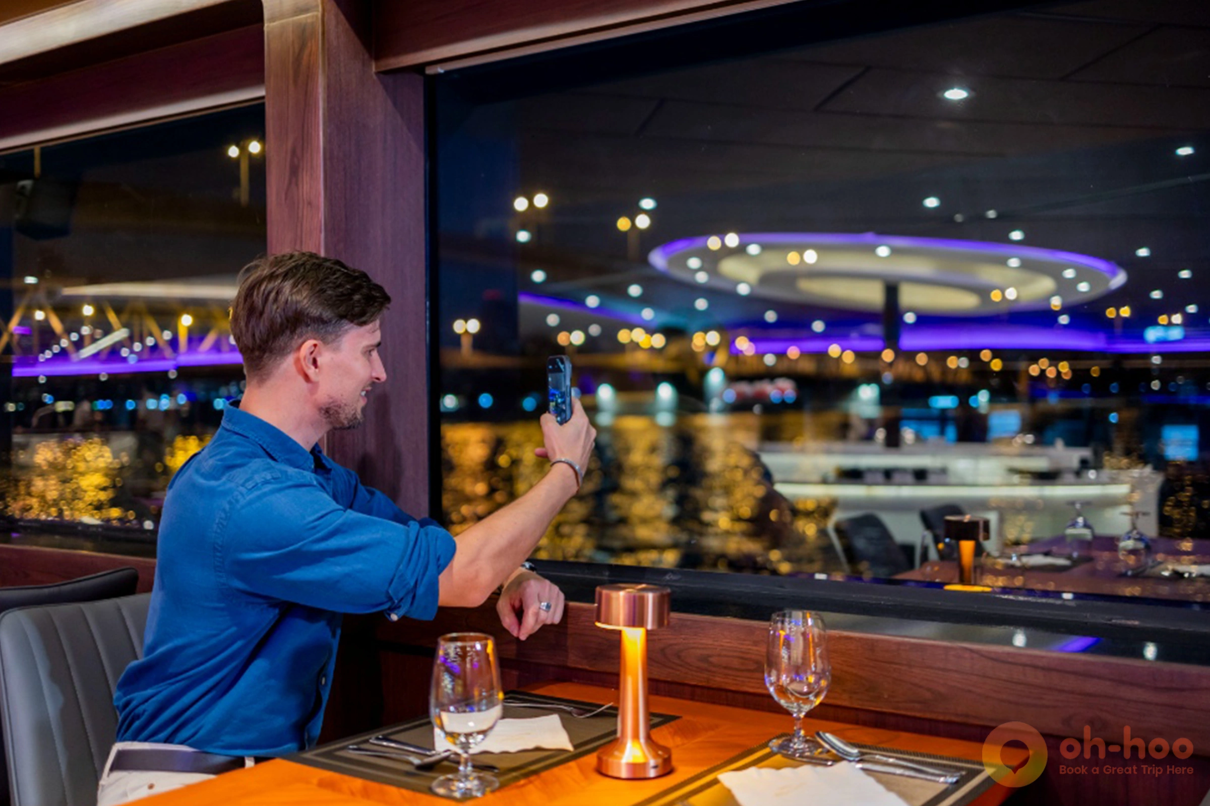 Dressed in smart casual clothes on the deck of a dinner cruise boat with the Bangkok river skyline at dusk