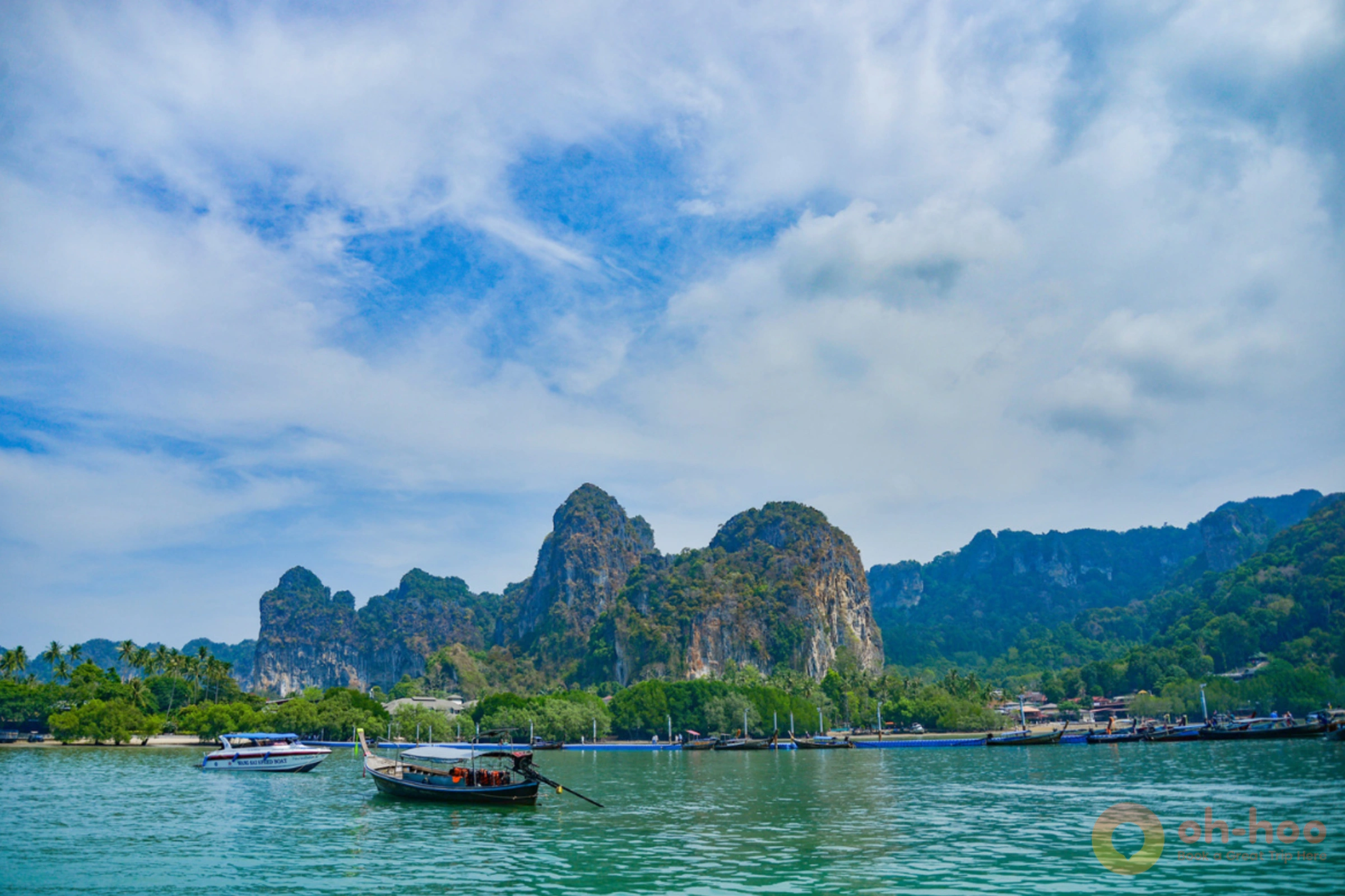 Longtail boat anchored between limestone cliffs in the turquoise Andaman Sea
