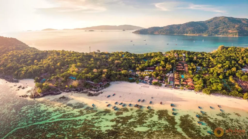 Aerial view of Koh Lipe Beach at sunset with white sand, turquoise water, coral reefs and lush tropical scenery