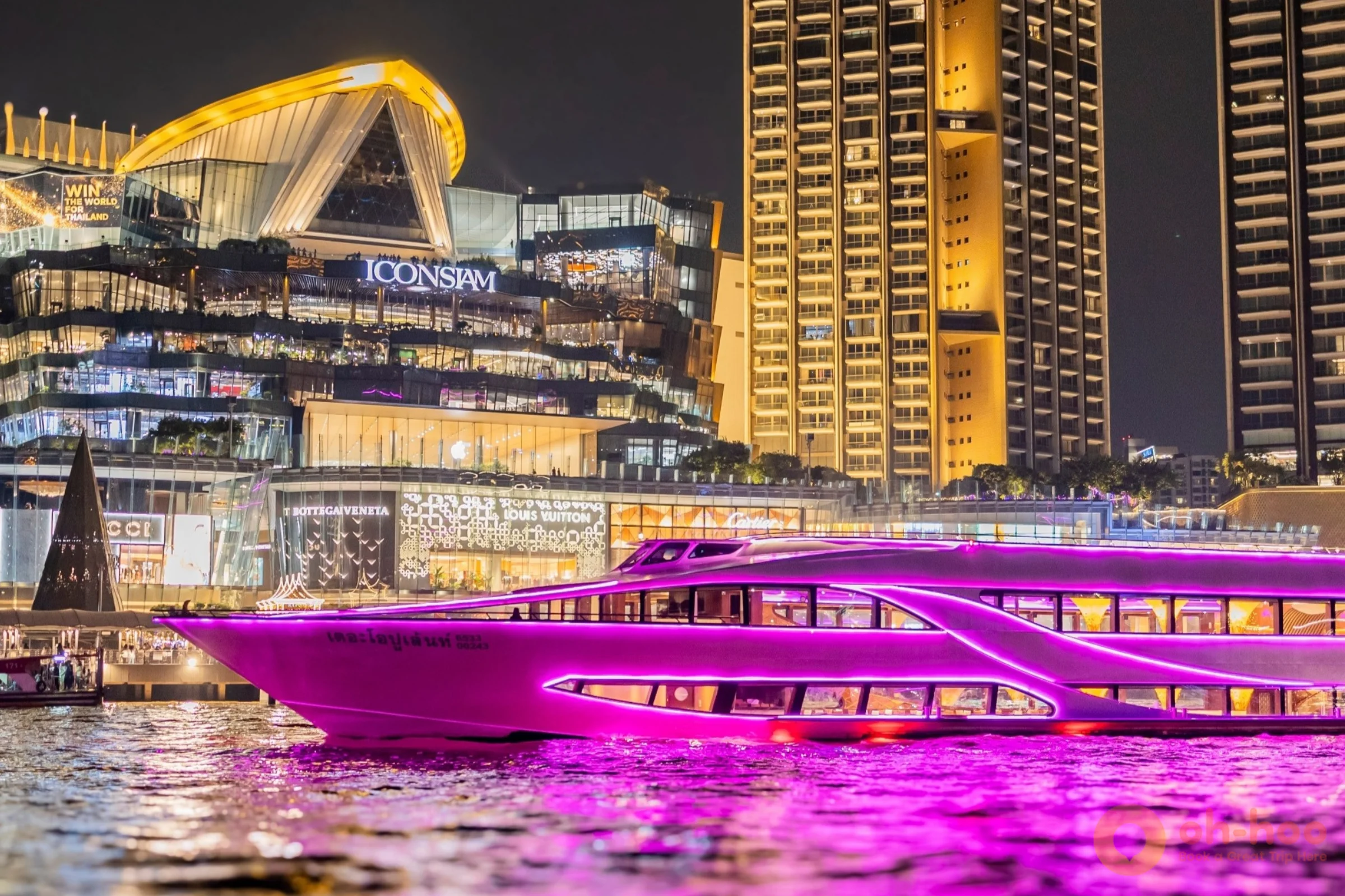 An illuminated dinner cruise boat at a Chao Phraya River pier in Bangkok at dusk