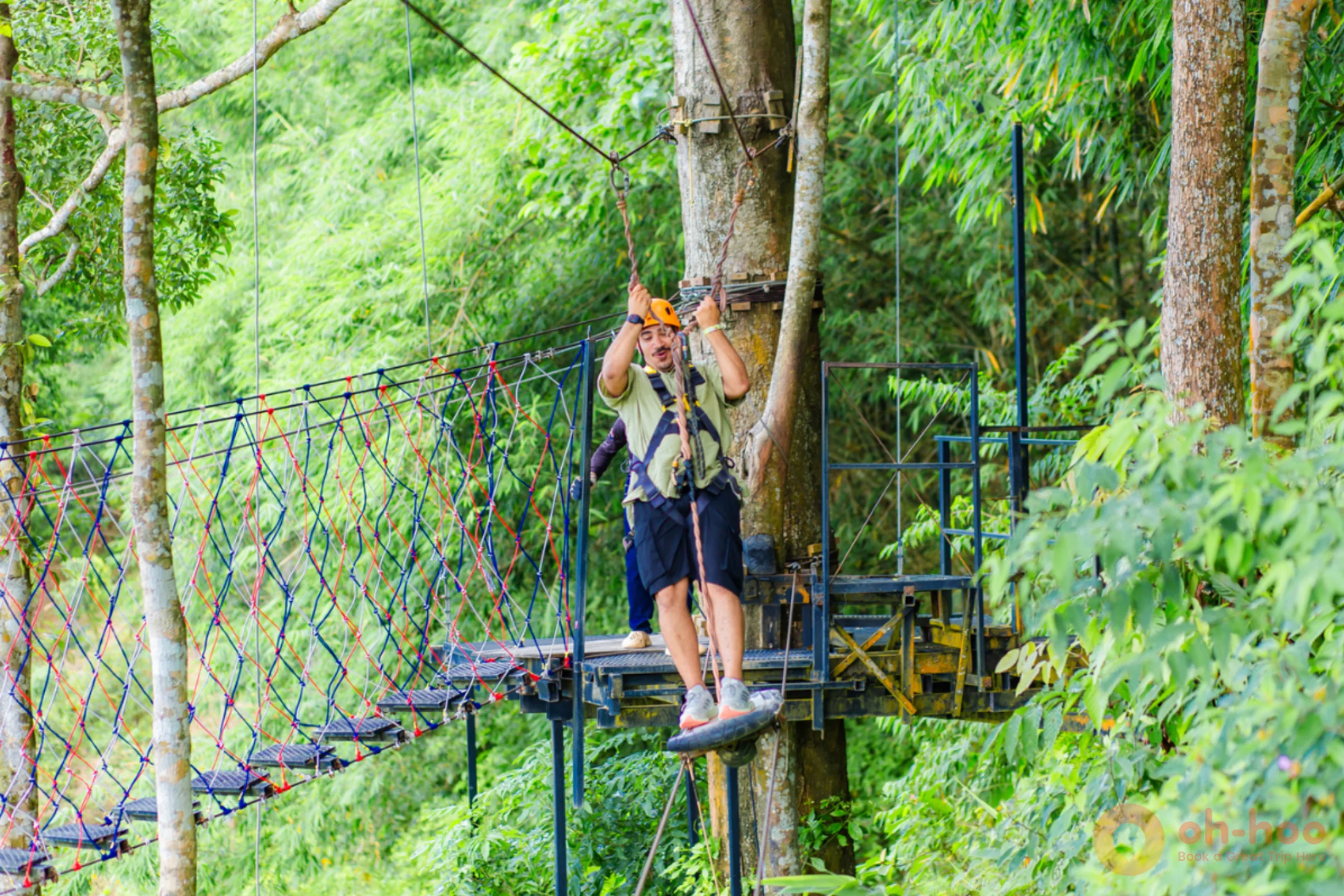 A rider in a full-body harness and helmet gliding along a zipline above the jungle canopy in Phuket
