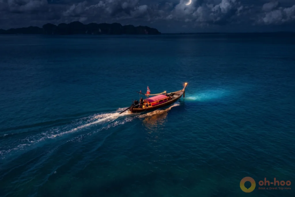 Aerial view of a jungle-covered limestone island and turquoise shallows with longtail boats on the sandbar in Krabi