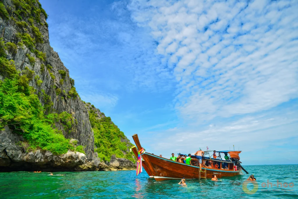 Longtail boat anchored off a limestone island on a snorkelling trip from Koh Lanta