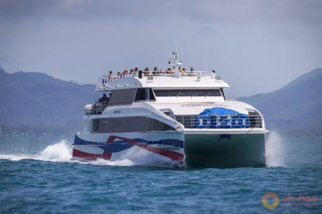 Passengers boarding a high-speed catamaran ferry beside a waiting transfer coach at a Krabi pier