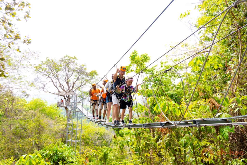 Visitor crossing a rope bridge between platforms at a jungle adventure park in Phuket