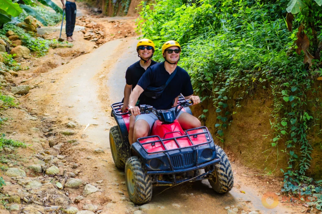 Riders on ATV quad bikes on a red dirt track through the Phuket jungle