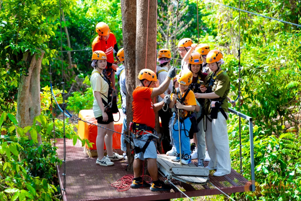 Guide checking a visitor's harness and helmet at the start of a Phuket zipline course