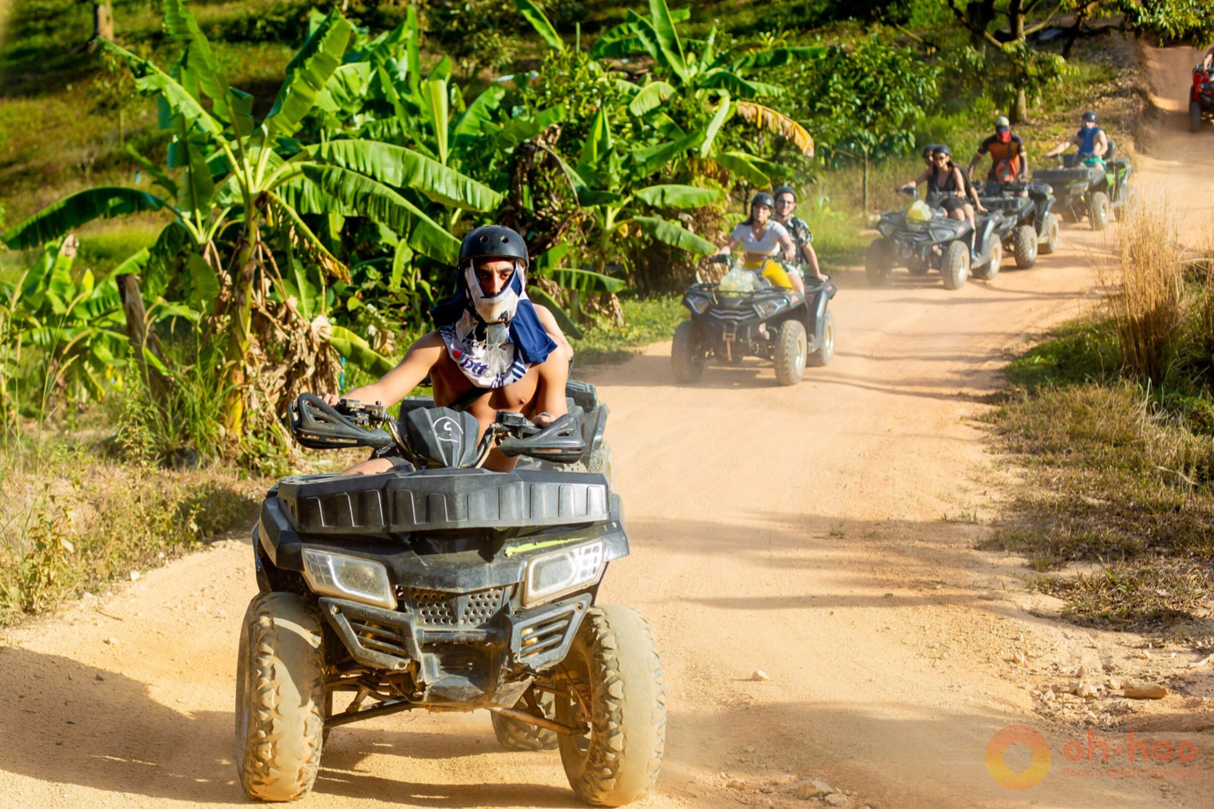 Rider on a quad bike splashing through a muddy jungle track in Koh Samui