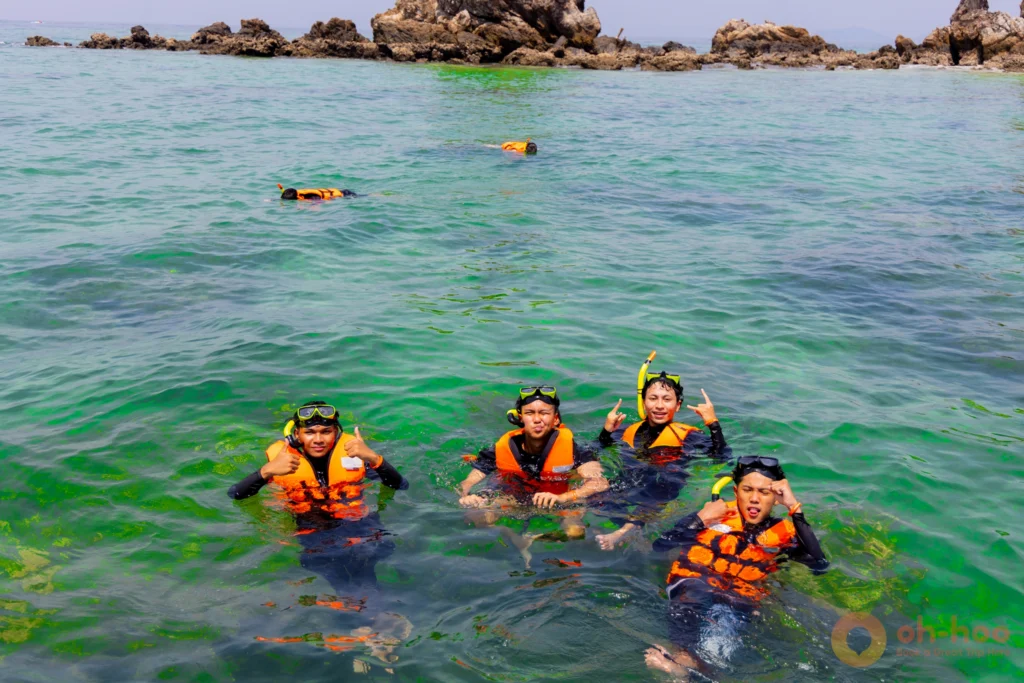 Snorkellers in life jackets in clear water beside a boat at Khai Nui island