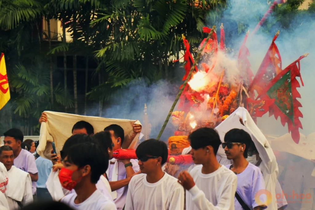 A spectator wearing protective earplugs amidst smoke and firecrackers at Phuket Old Town
