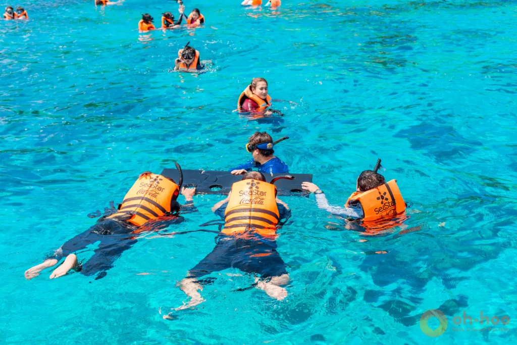 Snorkellers above a shallow coral reef in clear water at the Similan Islands
