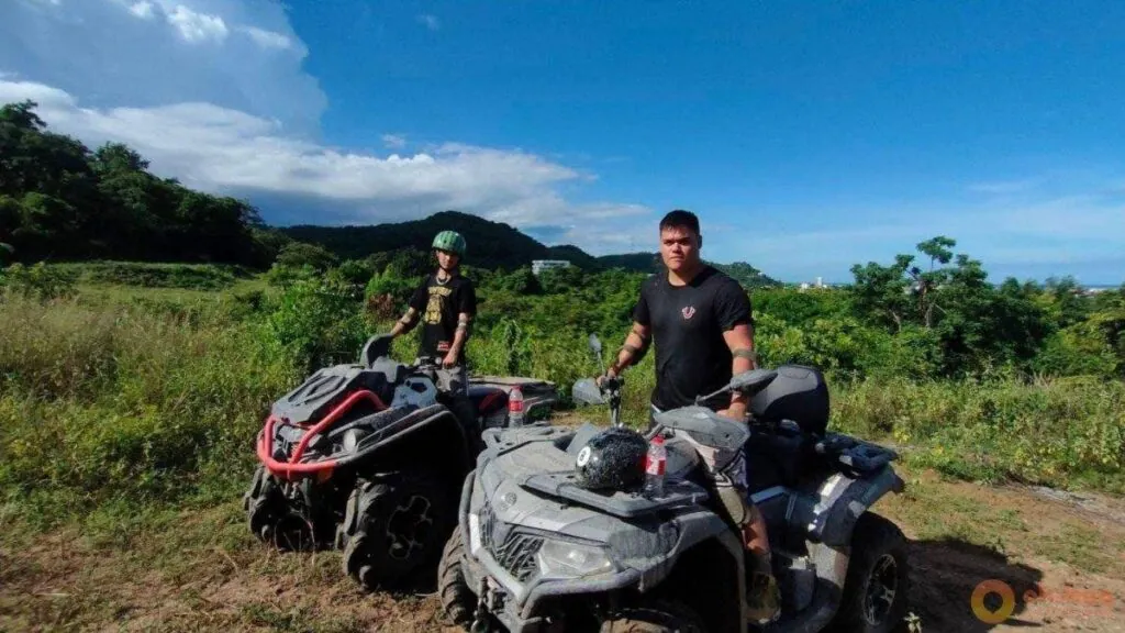 Two people pose on all-terrain vehicles along a rugged trail in the green hills of Hua Hin.