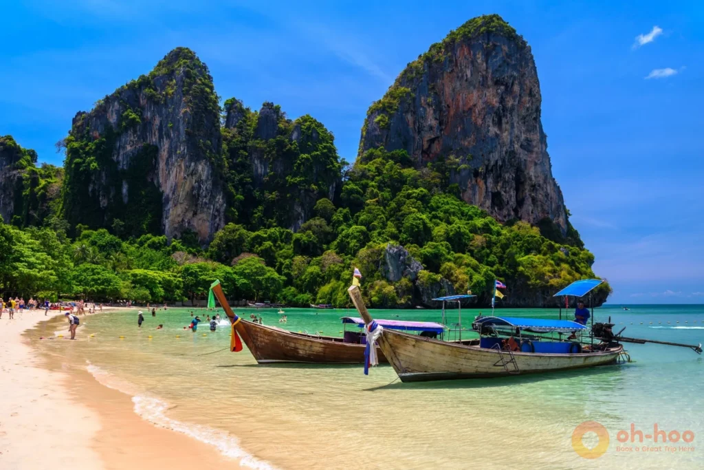 Rows of longtail boats anchored in clear water at Ao Nang Beach ready to take passengers to Railay