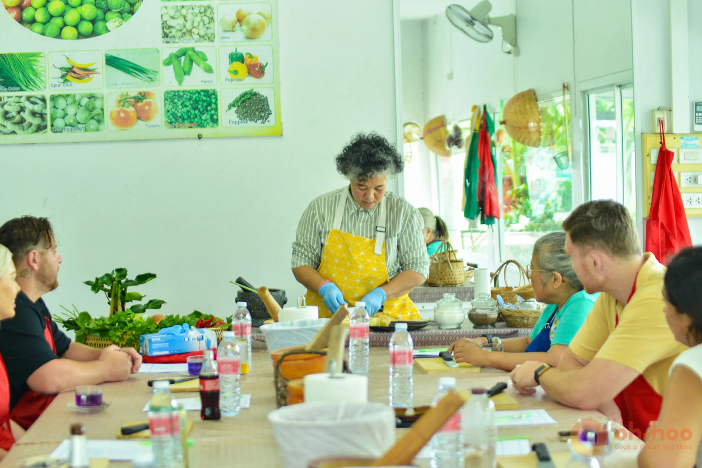 Instructor demonstrating Thai curry paste preparation using a traditional mortar and pestle during a cooking class