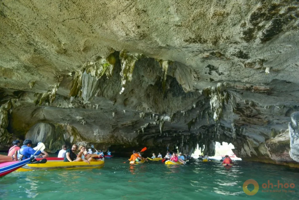 Tourists in a sea canoe exploring hidden limestone sea caves and emerald lagoons in Phang Nga Bay