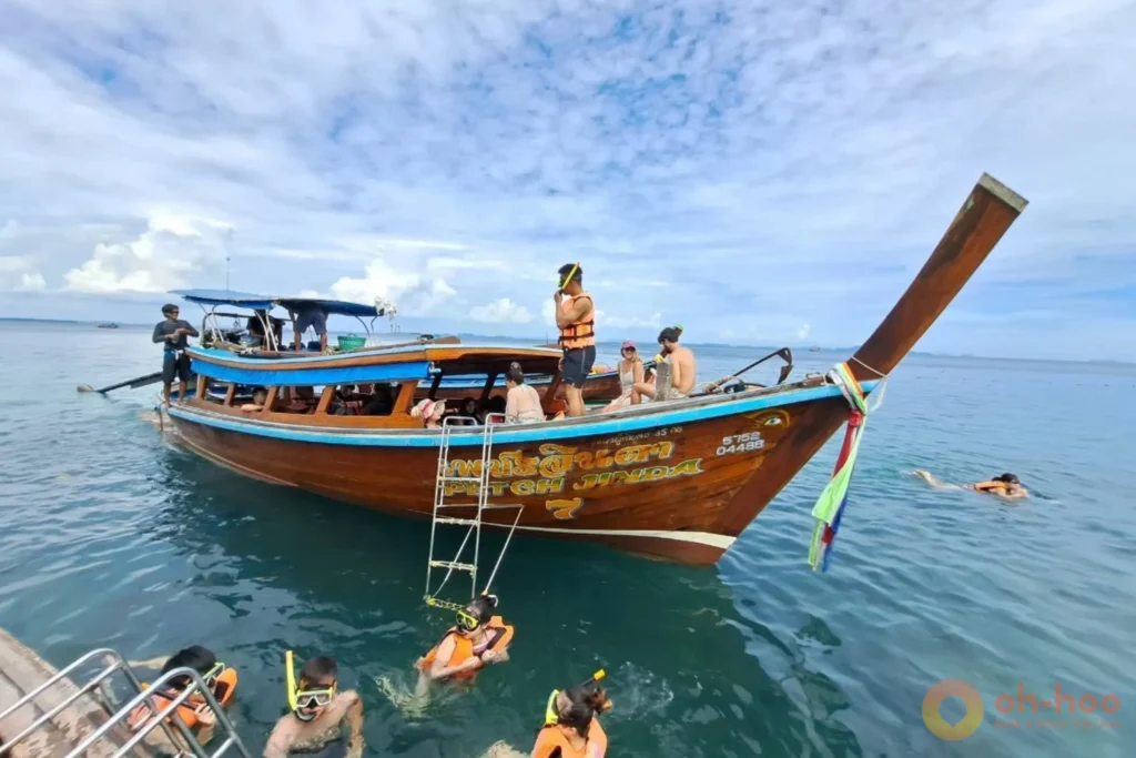 Longtail boats moored at Railay West beach under vertical limestone cliffs in Krabi