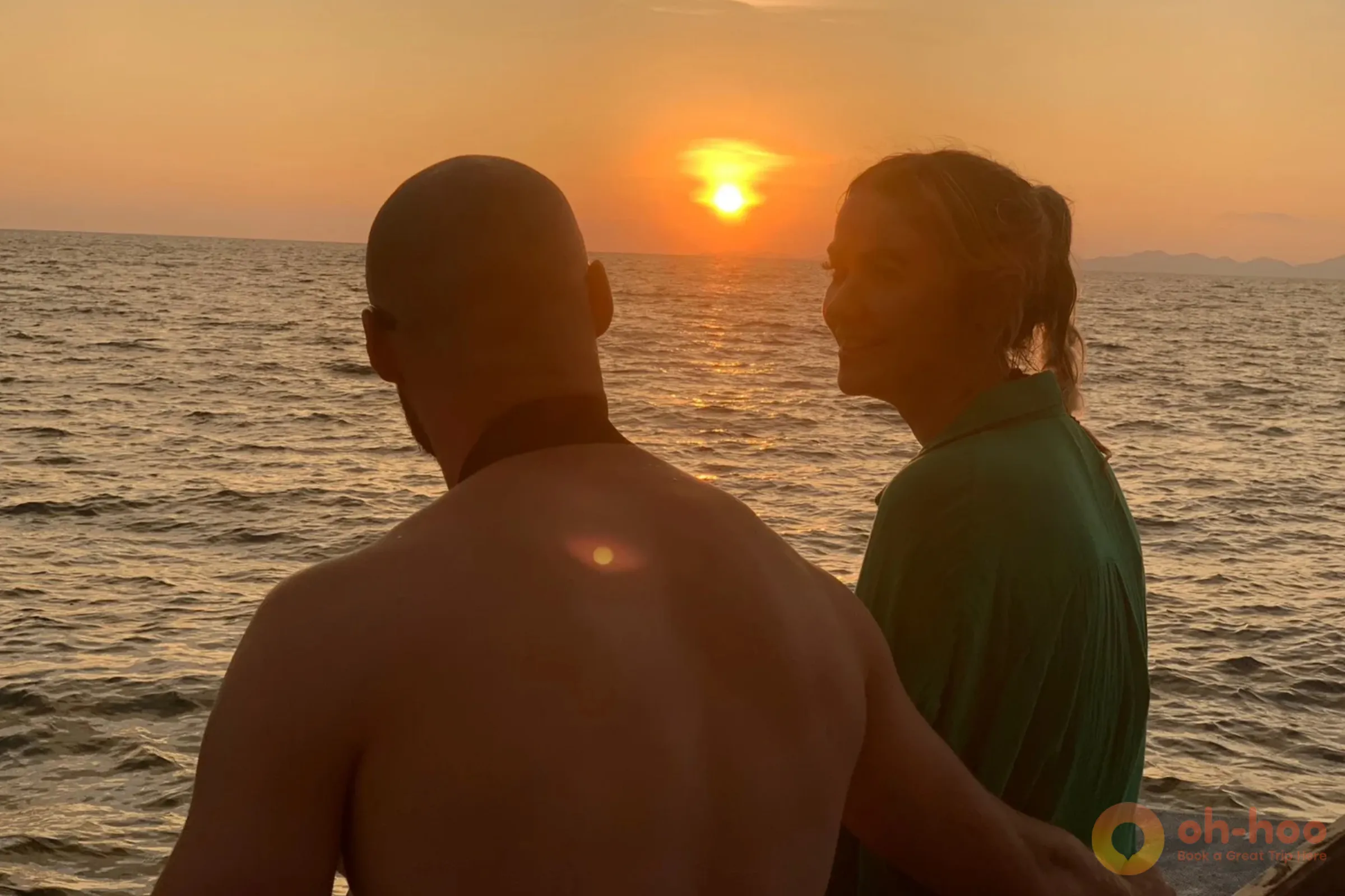 Couple watching a golden sunset over the Andaman Sea from a scenic tropical beach in Thailand